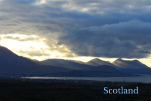 a mountain rage on the shore of a lake in Scotland at sunset