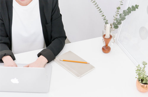 a woman sitting at a desk typing on a laptop